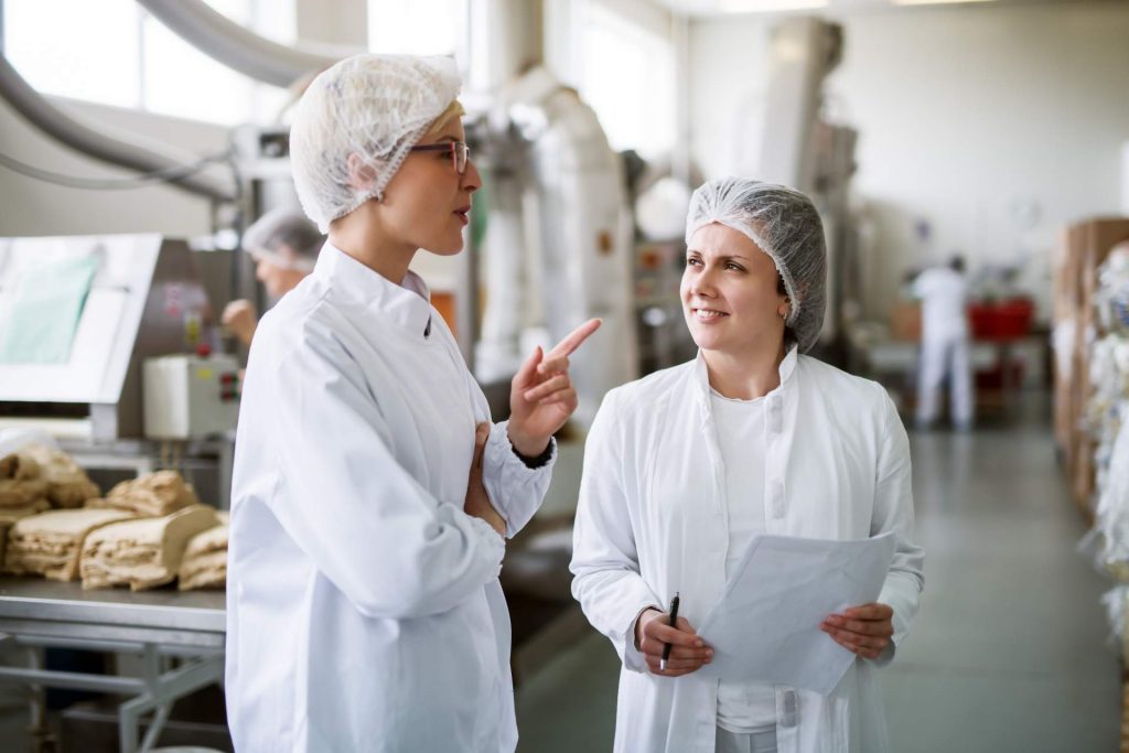 Deux travailleuses discutant en se tenant dans une usine alimentaire.